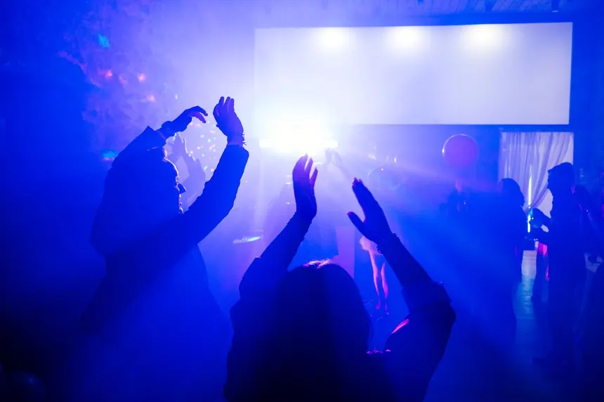 Pista de baile con luces azules y manos arriba en un evento con DJ Ponte
